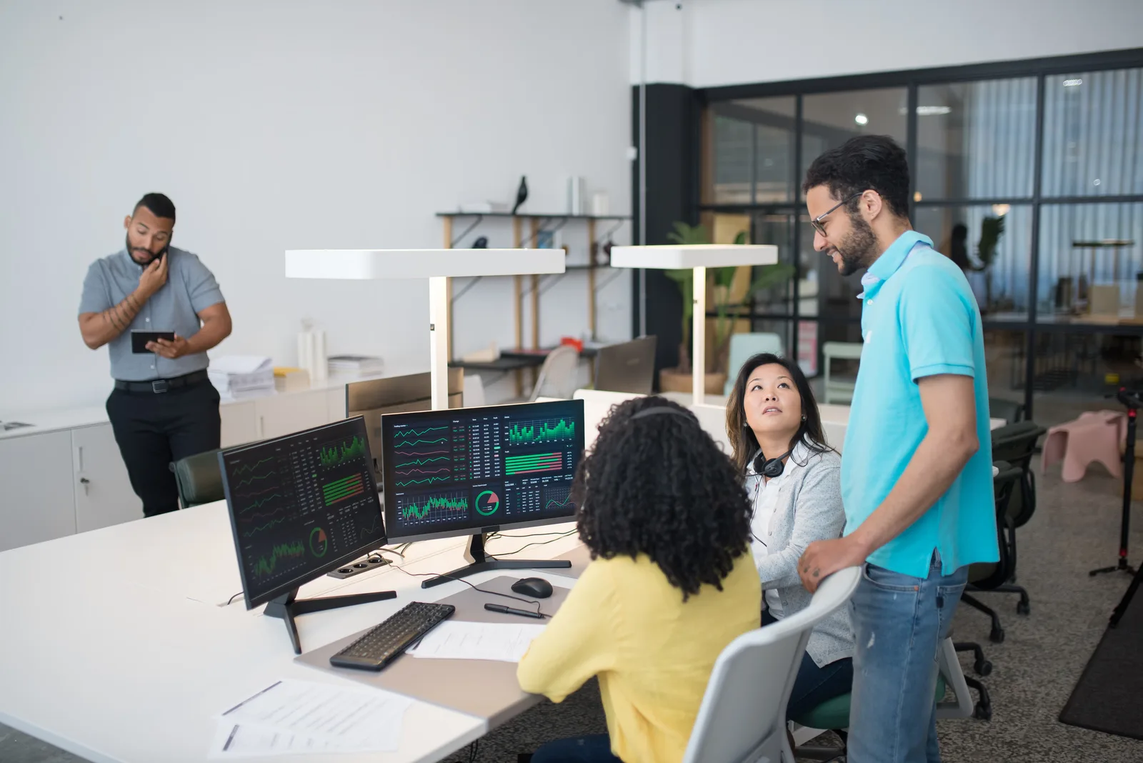 Office employees collaborate on financial data at modern workspace, engaging in teamwork and communication.