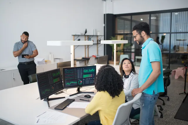 Office employees collaborate on financial data at modern workspace, engaging in teamwork and communication. CRM-system: funktioner för kunddata och försäljning